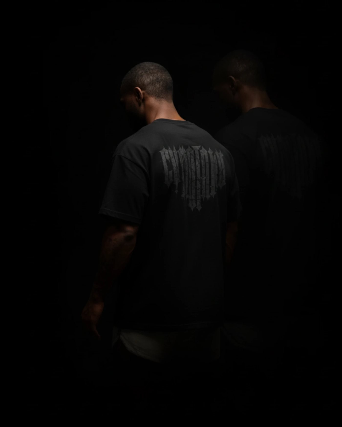 Dos atletas de GYMOTAKU de espaldas con polos negros de la colección